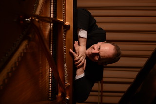 Jeremy Filsell leaning on a grand piano